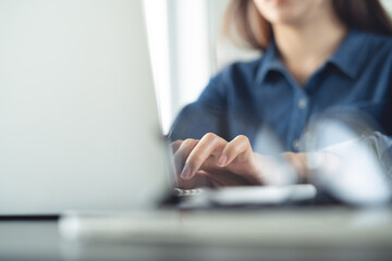 Closeup, business woman's hands working and typing on laptop computer keyboard on office table....