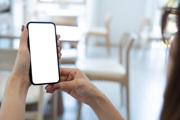 Mockup, woman's hand holding using mobile phone at coffee shop with copy space, white blank screen for text, mobile app design and advertising, online marketing, close up