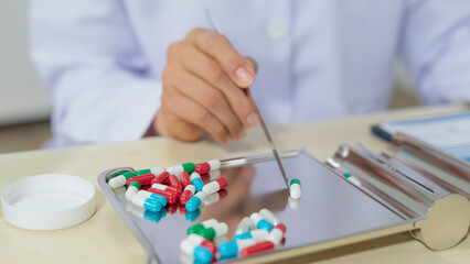 Pharmacist sorting colorful capsule medication on metal tray in pharmacy, healthcare concept