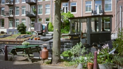 Defocused view of a boat moored along a canal in amsterdam with traditional houses in the blurred background under sunny skies.
