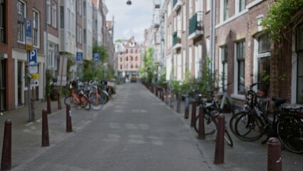 Blurry urban street scene in amsterdam with bicycles lining the narrow alleyway, showcasing the classic european architecture typical of the netherlands in a defocused view.