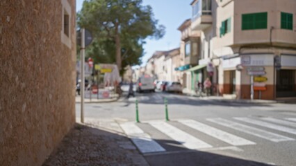 Obraz premium Blurred view of a mediterranean old town street with bokeh effect, showcasing a defocused scene with pedestrians and buildings under a bright blue sky.