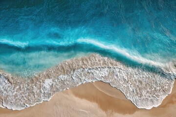 High-angle view of turquoise waves crashing on beige sand