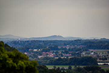 Weite Aussicht auf die sanften Hügel und das Dorf unter dem bewölkten Himmel in Deutschland