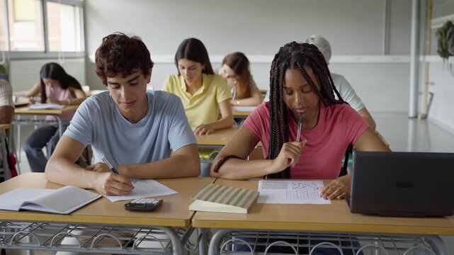 African American girl and caucasian guy students talking about class work learning together at school