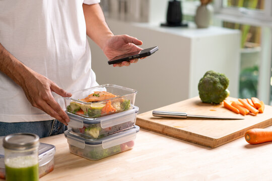 Person using smartphone app for calorie counting and photo sharing above homemade weight loss meal prep.