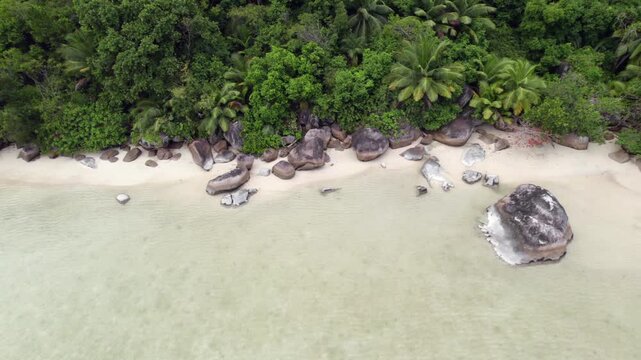 Drone footage of cap ternay beach, near granite stone and trees at low tide, Mahe, Seychelles 30fps 6