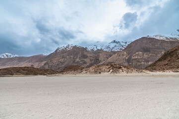 Peaceful Yarab Tso lake in Nubra Valley, Ladakh with white sandy shore, Himalayan mountains, and dramatic cloudy sky. Scenic nature, travel, and meditation background.