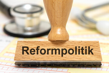 Ein Holzstempel ist beschriftet mit dem Aufdruck Reformpolitik als Symbolbild für notwendige...