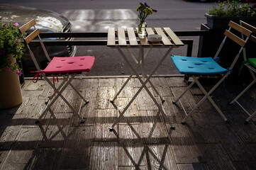 Street cafe in the morning. Empty terrace with chairs and wild flowers in glass bottles on the table