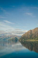 Mirror image perfection at Lake Wanaka. The still, deep blue water flawlessly reflects the rugged beauty of the mountains under a peaceful sky.