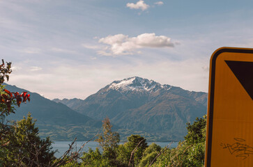 Clouds over the mountains with trees and traffic sign in the foreground