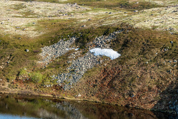 Rolling hills covered in vibrant green vegetation surround tranquil lakes under a blue sky. Serene landscape evokes a sense of peace and connection to nature. Kola Peninsula, Murmansk, Teriberka