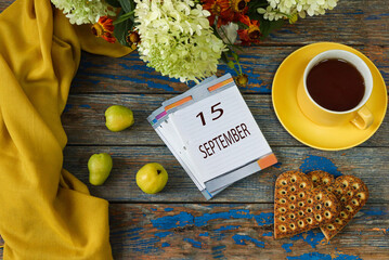 September 15 calendar: numbers 15, month name in English on a decorative calendar among quince, cup of tea and flowers