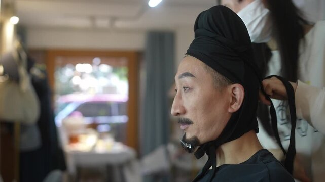 male actor in traditional Chinese costume is applying makeup