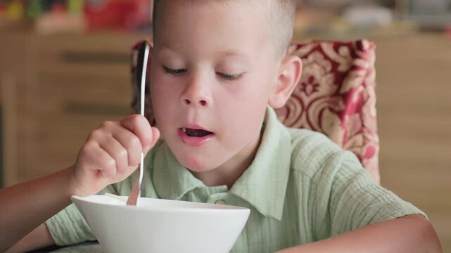 Boy 4 years trying eat spaghetti pasta difficulty slurping noodles closeup face child concentration food effort eating skill early development meal time learning self feeding family moment preschool