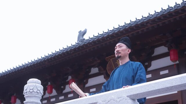 A man in traditional Chinese attire stands on the veranda of an ancient temple gazing into the distance
