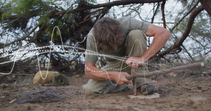 After placing baseboard, survivalist drilling spindle, creating friction to start fire