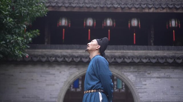 A young man in traditional Chinese attire gazes upward at an ancient courtyard gate with brick walls and hanging lanterns