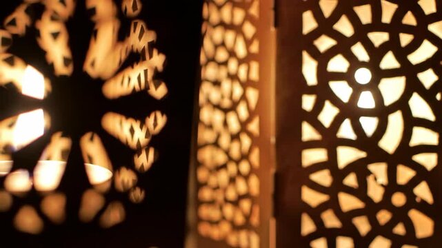 Warm candlelight glowing through an ornate pattern in the darkness.