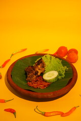 Grilled chicken served on a mortar and pestle after cooking. Fried chicken with tomato sauce, cucumber, and lettuce. A meal served morning, noon, and night. Asian food. 