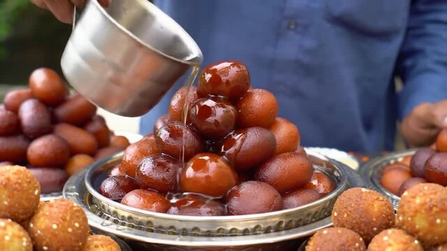 man hand pouring sugar syrup Gulab jamun , gulaab jamun golden bowl Indian sweet food mithai 4K slow motion footage Egyptian Zalabia balls dessert delicacy Pakistan, Ramadan
