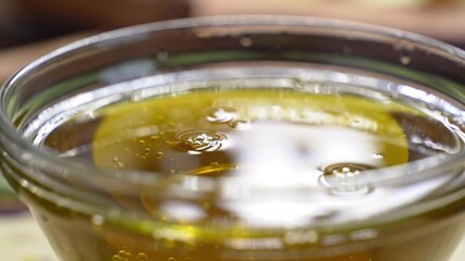 Natural golden olive oil with bubbles in glass bowl. Organic raw liquid closeup. Healthy ingredient for cooking - Powered by Adobe