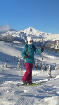 COPY SPACE: Young Caucasian woman on a ski touring trip to Slovenia hikes up a snow covered hill overlooking the picturesque untouched valley. Fit female tourist splitboarding in Velika Planina.