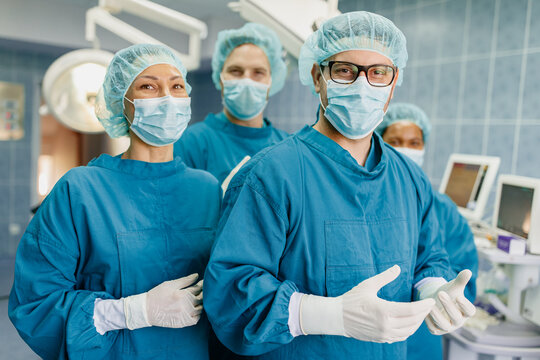 Healthcare Professionals Wearing Surgical Masks And Sterile Gowns During Medical Procedure In Modern Hospital Operating Room