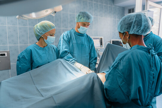 Team of Surgeons in Blue Surgical Gowns Performing an Operation in a Modern Operating Room