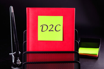 Concept of D2C Direct to customer, word D2C on a sticker on a red notebook on a black background