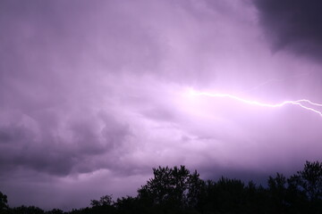 bright lightning in the night sky, makes the clouds purple, lightning lights up the night sky purple, lightning before a downpour