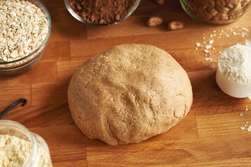 Ball of raw dough made of whey protein powder, ground oat flakes, vanilla and nut butter - preparation of homemade protein bars