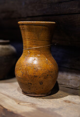 An antique ceramic jug stands on a wooden shelf.