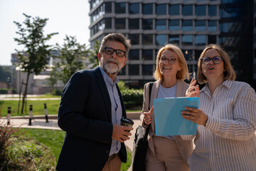 Multicultural business group discussing upcoming projects outdoors in modern city corporate district with good vibes	