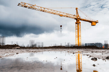 Construction site crane concrete reflection under storm cloud shows workmanship and craft with steel rod and muddy ground calm after rain