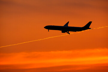 美しい太陽・光・雲・空を背景に飛ぶ航空機