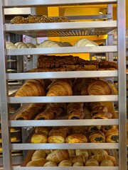 rack filled with various baked goods, primarily croissants and similar pastries.