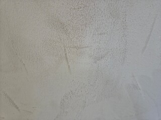 Textured light gray concrete wall with faint darker gray smudges or marks.