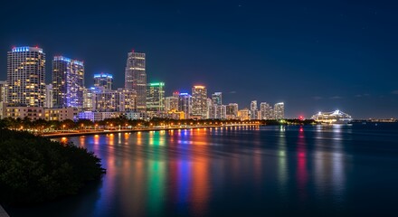 Fototapeta premium Miami Skyline at Night - Vibrant City Lights Reflecting on the Bay.