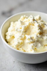 Close-up of creamy, fresh cottage cheese in a white bowl, highlighting its texture and lumps  Perfect for healthy eating and breakfast recipes ,  rustic,  dairy product