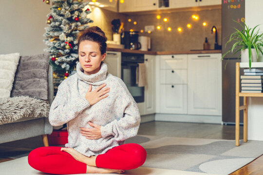 Woman meditating in lotus pose at home during Christmas holidays - Powered by Adobe