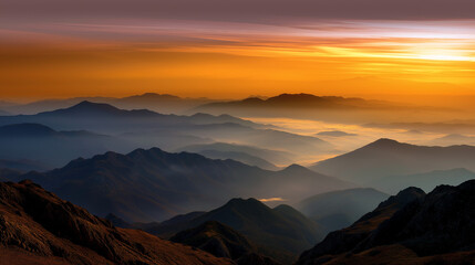 Obraz premium Silhouette of jagged mountain ridges above a blanket of fog, the first sun rays illuminating the sky in warm tones.