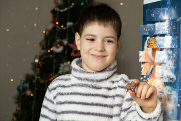 A happy child took out chocolate from the advent calendar. Preparing for Christmas