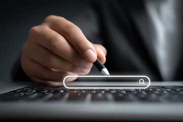 A hand holding a pen hovers over a laptop keyboard with a search bar graphic displayed, symbolizing online research or digital interaction.