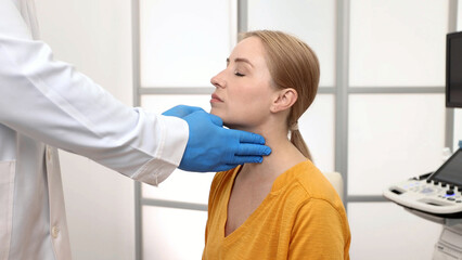 Thyroid gland exam and treatment. Doctor palpates of woman's neck for diagnostics of thyroid...
