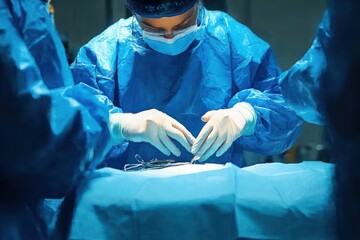 Surgeons in blue surgical gowns and masks performing an operation with focused precision in a sterile operating room environment