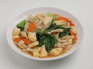 Stir fried tofu, mushroom and vegetables with sauce on white plate