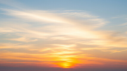 Fototapeta premium A high-definition photograph of a serene sunset, featuring a soft gradient of colors from warm orange and pink near the sun to a calm blue at the top of the frame