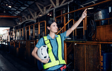 Portrait of professional woman engineer in white hardhat standing and working in train factory.